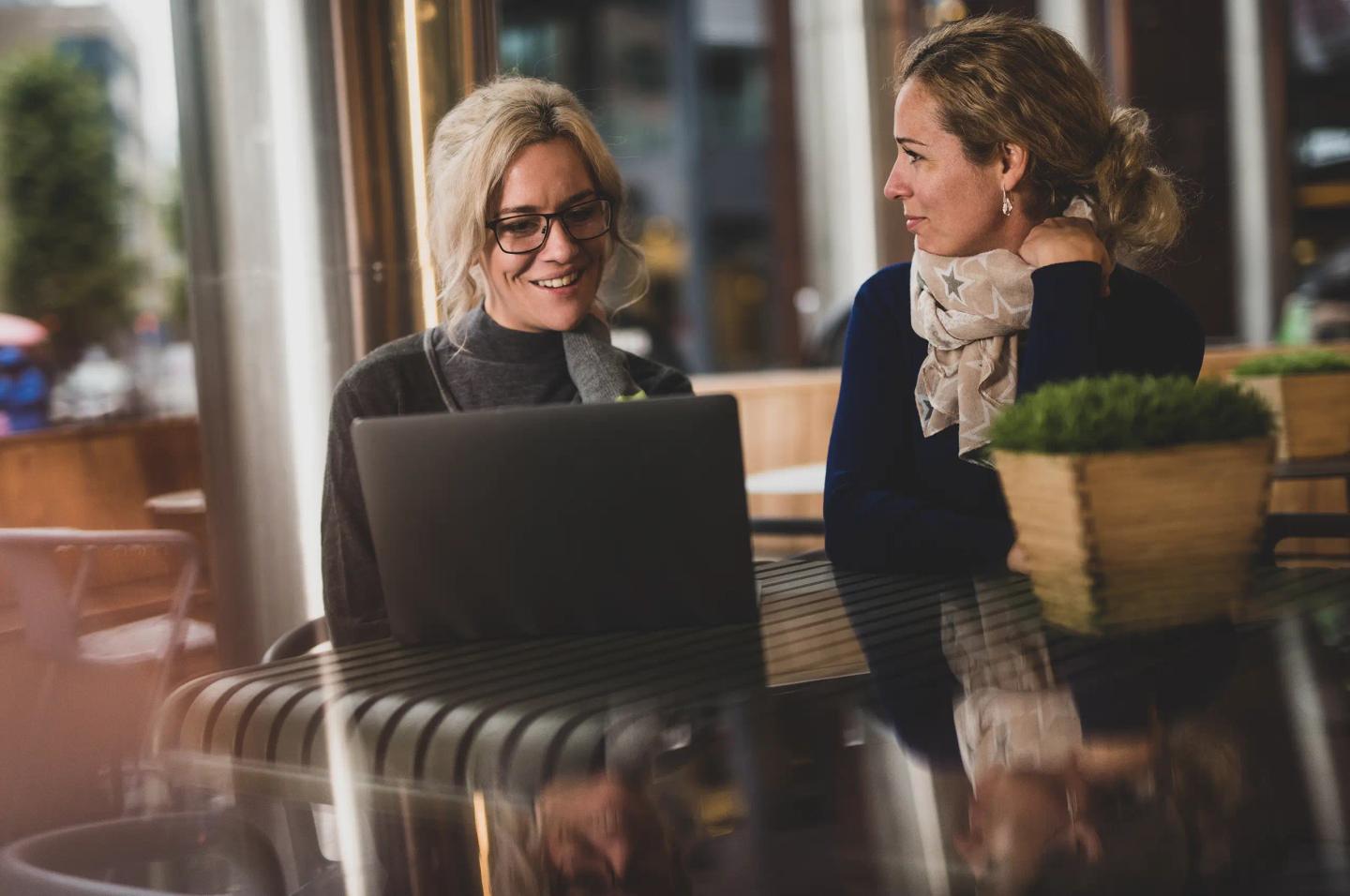 To personer i hyggelig samtale med hver sin laptop.