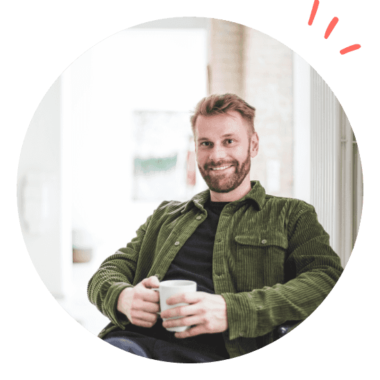 En glad leder smiler med en kaffekopp i hånden