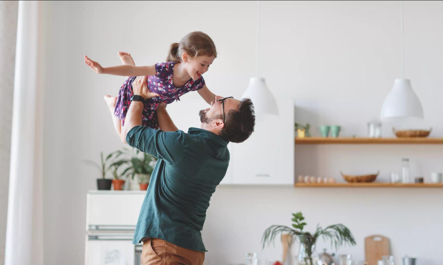 En forelder leker med barnet sitt ved å løfte det opp i luften.
