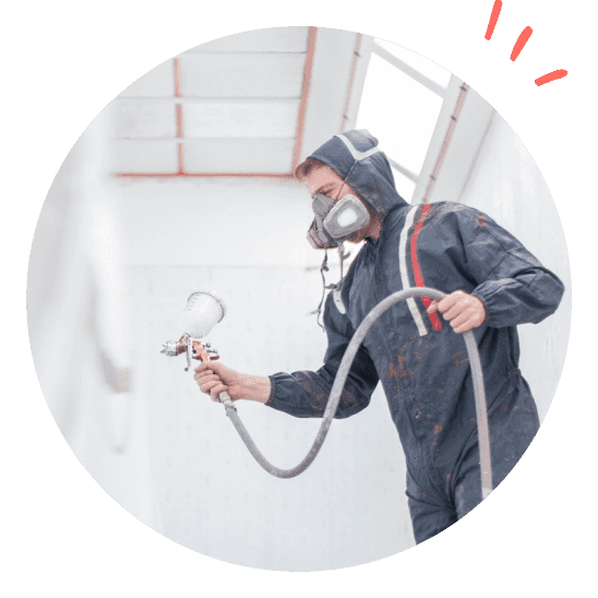 Man with mask and safety suit spray-painting indoors.